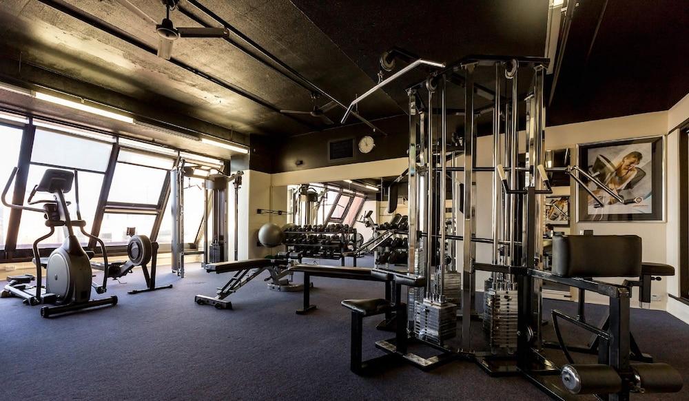 Stamford Grand Adelaide Otel Glenelg Dış mekan fotoğraf The photo shows the interior of a gym or fitness room. It includes various exercise equipment, such as a multi-station weight machine and rowing machine. The space is well-lit with large windows allowing natural light in, and the walls are decorated 