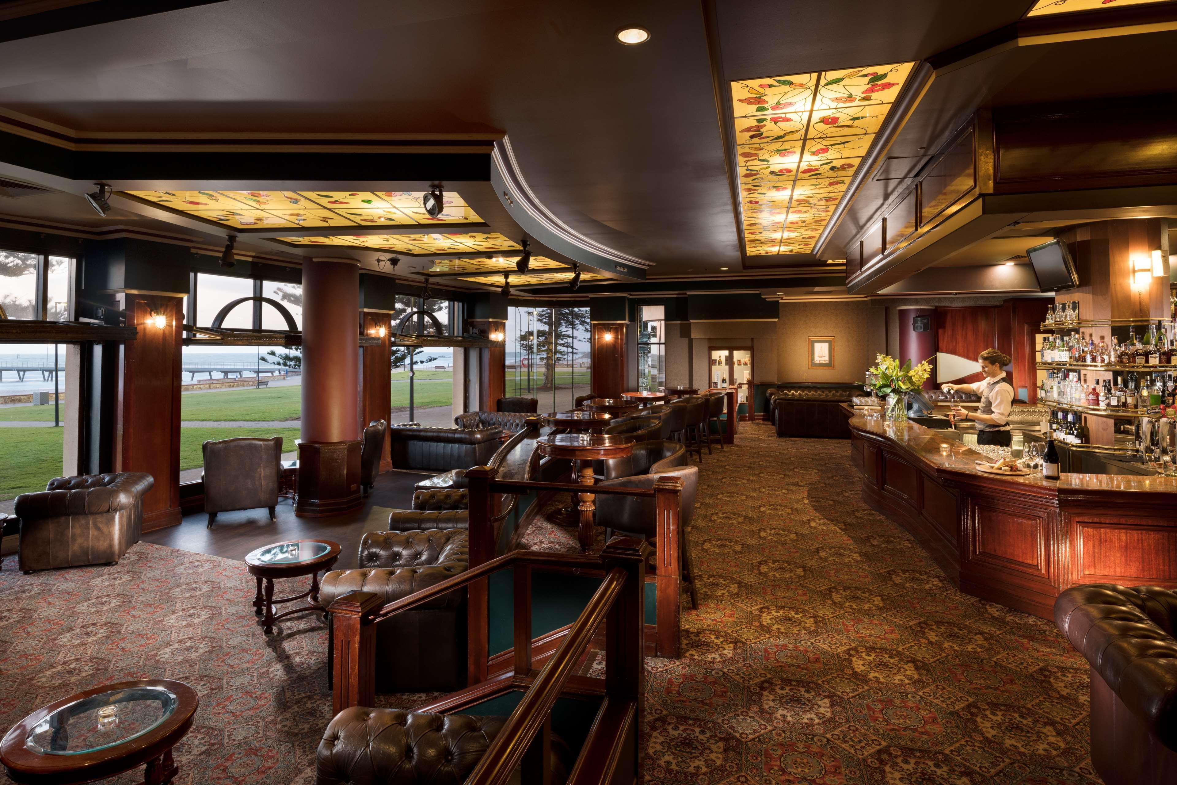 Stamford Grand Adelaide Otel Glenelg Dış mekan fotoğraf The photo depicts a stylish and upscale bar or lounge area. The interior features elegant wooden furniture, including plush chairs and tables. The ceiling is adorned with decorative elements, and the lighting provides a warm ambiance. A bar counter c