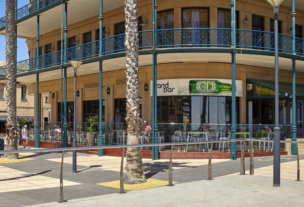 Stamford Grand Adelaide Otel Glenelg Dış mekan fotoğraf The photo shows a corner of a building that houses a bar with the name "End Bar" prominently displayed. It's a multi-level structure with balconies featuring decorative railings. In front of the bar, there are tables and chairs, indicating a dining o