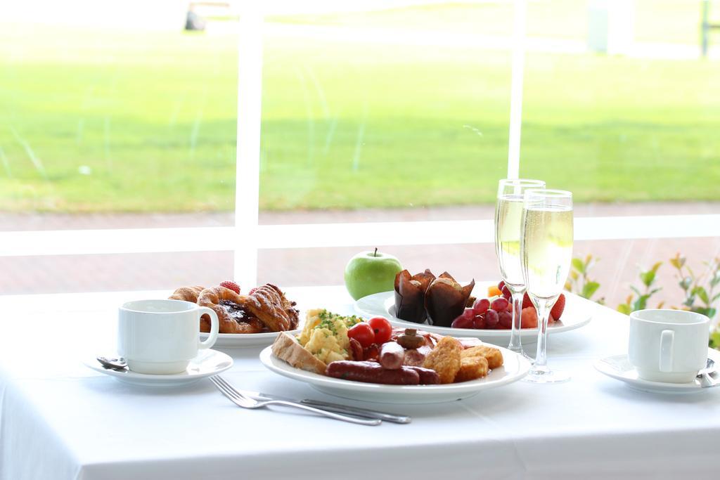 Stamford Grand Adelaide Otel Glenelg Dış mekan fotoğraf The photo displays a beautifully arranged breakfast setup on a white tablecloth. In the center, there is a large white plate with a variety of foods, including eggs, sausage, and fresh fruit. Surrounding the plate are a few other food items, such as 